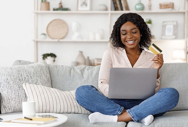 Positive Young Black Girl Using Laptop and Credit Card At Home